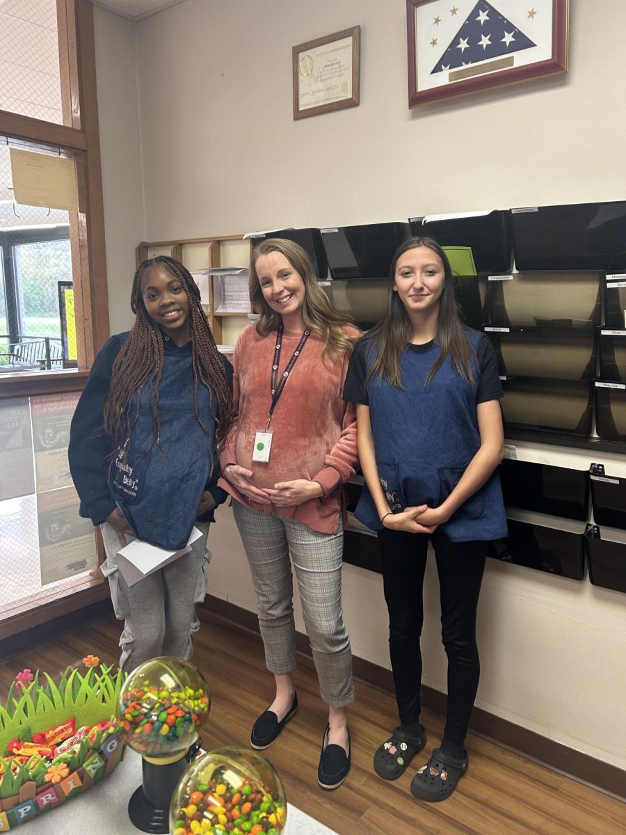 Pregnant Dr. Rucinski (center) poses with students Aaliyah Bartholomew (left) and Elizabeth Corcoran (right) as they wear the empathy belly for parenting class. On Nov. 1, students in the class got to experience what it’s like to be pregnant and how difficult it is to do day-to-day tasks while being pregnant. 